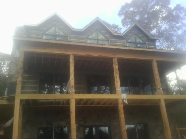 Dormers and porch framing on a large log home under construction — Roof Coating work by our crew in Hodges