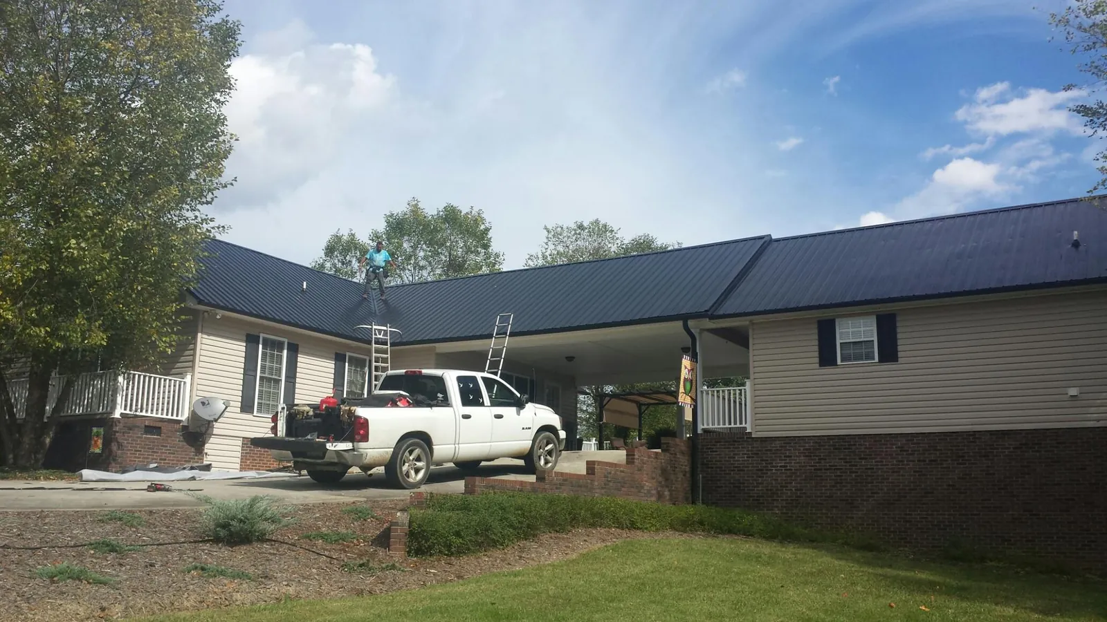 Black metal roof over a home and attached breezeway with ladders set in Hodges